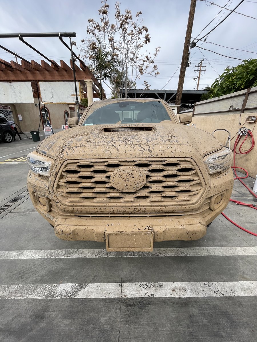 Black Toyota Tacoma covered head to grille in dried mud before full detail at Fair Oaks Car Wash