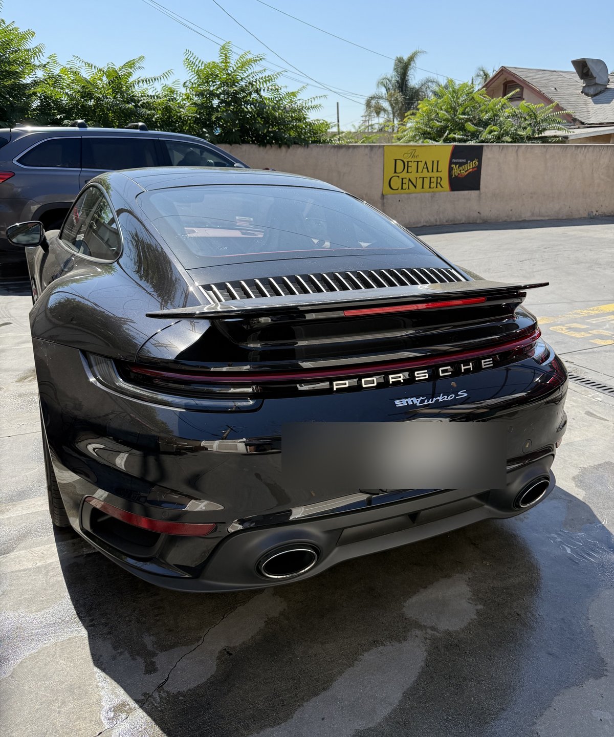 Black Porsche 911 Turbo S detailed at Fair Oaks Car Wash, with the Detail Center signage in the background